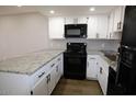 Bright kitchen featuring white cabinets, granite counters, and modern black appliances at 2144 E Center Ln # 3, Tempe, AZ 85281