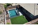 An aerial view of the backyard showcasing a refreshing pool, lush artificial turf, and privacy fencing at 31324 N 26 Glen Gln, Phoenix, AZ 85085