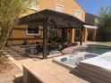 Backyard patio with a covered pergola, outdoor seating, a pool, and a hot tub at 35743 W Cartegna Ln, Maricopa, AZ 85138