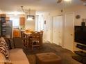 A staged living room with hardwood dining table, carpet, neutral walls, and a view into the kitchen at 455 S Mesa Dr # 104, Mesa, AZ 85210
