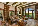 Elegant living room with beamed ceilings, a large window, and custom draperies overlooking a garden at 7710 E Golden Eagle Cir, Gold Canyon, AZ 85118