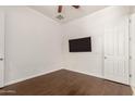 A simple bedroom with wood floors features a ceiling fan and wall-mounted TV at 10502 W Bronco Trl, Peoria, AZ 85383