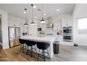 Modern kitchen featuring stainless steel appliances, white cabinets, a large island with seating and wood look tile floors at 11019 E Tiburon Ave, Mesa, AZ 85212