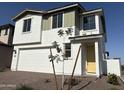 Charming two-story home with a white exterior, a two-car garage, and newly planted front yard tree at 18001 W Lupine Ave, Goodyear, AZ 85338