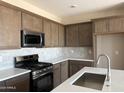 Well-lit kitchen featuring new appliances, granite countertops and a stylish tile backsplash at 18162 W Larkspur Dr, Goodyear, AZ 85338