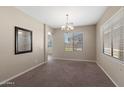 Carpeted dining room with large windows, neutral walls, and a decorative mirror and chandelier at 2036 E Carob Dr, Chandler, AZ 85286