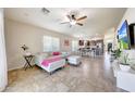 Open-concept living room with tile flooring and a ceiling fan, seamlessly flowing into the dining and kitchen areas at 2716 W Sunland Ave, Phoenix, AZ 85041
