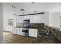 Bright kitchen with white cabinets, stainless steel appliances, granite countertops, and wood-look floors at 41839 W Avella Dr, Maricopa, AZ 85138
