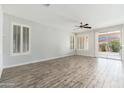 Bright living room with wood-style floors, ceiling fan, plantation shutters, and patio access at 6180 W Oraibi Dr, Glendale, AZ 85308
