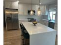 Bright, modern kitchen featuring white cabinets, stainless steel appliances, an island, and stylish pendant lighting at 7802 E Hubbell St, Scottsdale, AZ 85257
