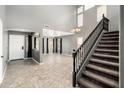 Bright living room with soaring ceilings, a staircase with dark wood banister, and gray walls creating a modern aesthetic at 9735 W Kirby Ave, Tolleson, AZ 85353