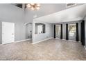 Open-concept living area featuring high ceilings, neutral gray walls, tile floors, and plenty of natural light from the window at 9735 W Kirby Ave, Tolleson, AZ 85353