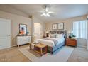 Bright bedroom with a ceiling fan, a large window, and neutral decor with a white door and dresser at 10722 W Irma Ln, Peoria, AZ 85373