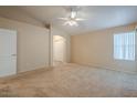 Large bedroom with neutral carpet, ceiling fan, and a door leading to another room at 10722 W Irma Ln, Peoria, AZ 85373