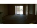 A neutral living room with a sliding glass door to the exterior with plush carpeting at 13861 W Elm St, Surprise, AZ 85374