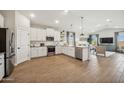 Open concept kitchen with stainless steel appliances, white cabinetry, and wood-look flooring at 42440 W Peters Dr, Maricopa, AZ 85138