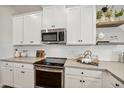 Kitchen with white cabinets, tile backsplash, stainless steel appliances and quartz countertops at 42440 W Peters Dr, Maricopa, AZ 85138