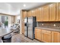 Open kitchen with stainless steel fridge, wooden cabinetry, and view to adjacent living area at 450 W Mountain Sage Dr, Phoenix, AZ 85045