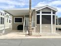 Charming manufactured home with covered parking, desert landscaping, and a welcoming front porch entry at 591 S Ironstone Dr, Apache Junction, AZ 85119