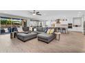 Open-concept living room flows to kitchen, featuring tile floors, a large sectional sofa, and backyard access at 10353 E Trillium Ave, Mesa, AZ 85212