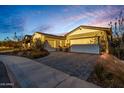 Home featuring desert landscaping, pavers, and a three-car garage under a vibrant sky at 11385 N Luckenbach St, Surprise, AZ 85388