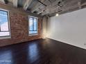 Spacious living room features exposed brick wall, high ceilings, large windows, and hardwood floors at 114 W Adams St # 302, Phoenix, AZ 85003