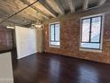 Inviting living area with exposed brick, concrete ceiling, hardwood floors, and industrial-style lighting at 114 W Adams St # 302, Phoenix, AZ 85003