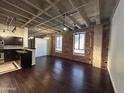 Open-concept living space with a modern kitchen, exposed brick, concrete ceilings, and hardwood floors at 114 W Adams St # 302, Phoenix, AZ 85003