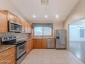 Functional kitchen featuring wood cabinets, stainless steel appliances, laminate countertops, and neutral tile floors at 12613 N 51St Dr, Glendale, AZ 85304