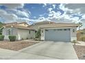 View of the exterior showcasing a long driveway, two car garage, manicured bushes, and a desert rock yard at 1383 E Prescott Pl, Chandler, AZ 85249