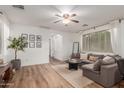 Bright living room featuring wood floors, a ceiling fan, and a comfortable gray sectional sofa at 15488 W Aster Dr, Surprise, AZ 85379