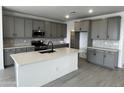 Modern kitchen features gray cabinets, stainless steel appliances, white quartz countertops, and an island with a sink at 17481 W Fulton St, Goodyear, AZ 85338