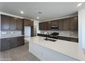 Modern kitchen features dark cabinetry, stainless appliances, and a large island with a sink at 17511 W Fulton St, Goodyear, AZ 85338