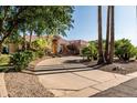 A circular driveway leads to a stone home surrounded by mature trees and landscaping at 2107 E Park Ave, Gilbert, AZ 85234