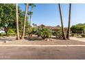 A stone home is framed by palm trees, lush landscaping, and a clear blue sky at 2107 E Park Ave, Gilbert, AZ 85234