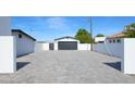 Long, spacious driveway with a white fence and a black garage door providing ample parking space at 11601 N 64Th Pl, Scottsdale, AZ 85254