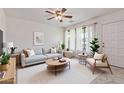 Bright living room featuring a neutral-toned sofa, modern decor, ample natural light, and a ceiling fan for added comfort at 2145 W Cholla St, Phoenix, AZ 85029