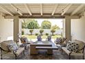 Covered patio with cushioned seating and a fire pit overlooking the beautifully landscaped backyard at 3813 N 37Th St, Phoenix, AZ 85018