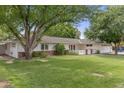 Beautifully landscaped home with lush green lawn, mature trees, and a charming white picket fence at 3817 E Highland Ave, Phoenix, AZ 85018