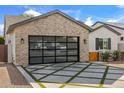 View of the modern glass-paned garage door and a driveway with geometric design at 4132 N 42Nd St, Phoenix, AZ 85018