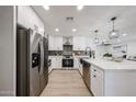 Modern kitchen featuring stainless steel appliances, white cabinets, stylish backsplash, and an island with quartz countertops at 4234 E Winnetka Dr, Phoenix, AZ 85044