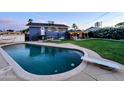 Inviting swimming pool and diving board with backyard patio and two-story home at dusk at 4644 W Berridge Ln, Glendale, AZ 85301