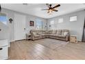 Spacious living room featuring wood-look tile, neutral paint, updated fan and a sectional sofa at 5741 W Warner St, Phoenix, AZ 85043