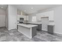 Bright kitchen featuring white cabinets, gray island, modern appliances, and stylish tile floors at 9310 W Washington St, Tolleson, AZ 85353