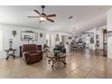 Spacious living room with tiled flooring, ceiling fan, and an open layout connecting to the dining area at 10465 W Windsor Blvd, Glendale, AZ 85307