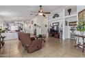 Open-concept living area featuring tile floors, a ceiling fan, and a view into the dining and kitchen areas at 10465 W Windsor Blvd, Glendale, AZ 85307