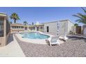 A clear in-ground pool with a rockscape in a backyard, a covered patio, and lounge chairs for enjoying the backyard at 1285 E Mcmurray Blvd, Casa Grande, AZ 85122