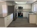 Well-equipped kitchen featuring stainless steel appliances, ample counter space, and updated gray vinyl flooring at 1452 E Emerald Ave, Mesa, AZ 85204