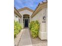 Inviting front entrance with a black door, desert landscaping, and a well-lit, charming walkway at 7214 E Rustling Pass, Scottsdale, AZ 85255
