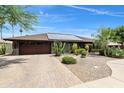 Exterior shot of a single-story home featuring desert landscaping, solar panels, and a brick driveway at 1656 W Meseto Cir, Mesa, AZ 85202